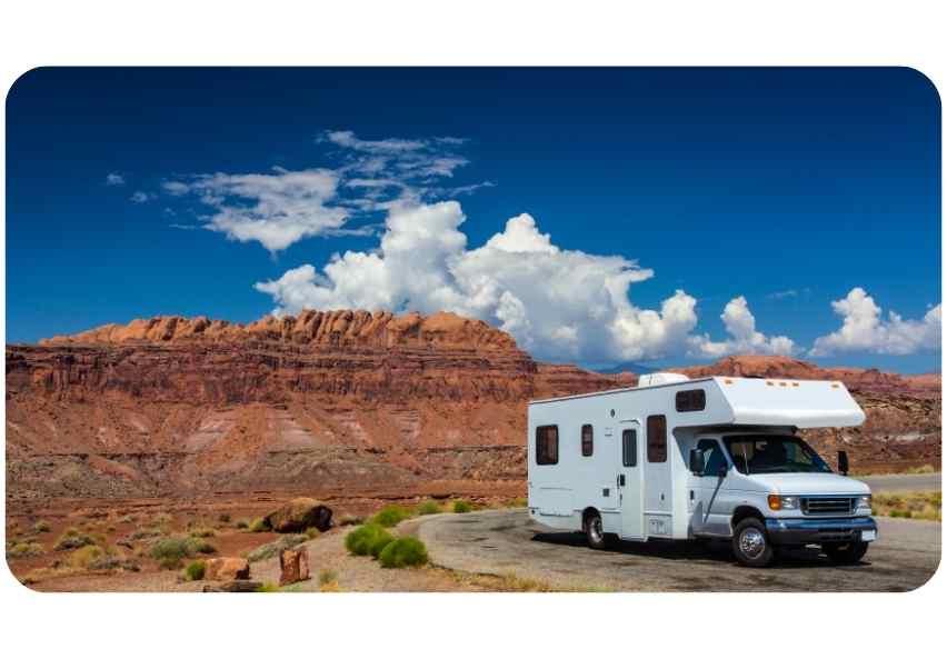Motorhome on a winding desert road beneath red rock cliffs